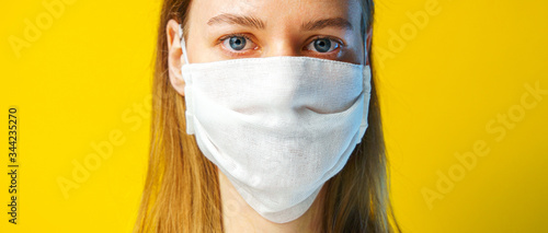Portrait of a woman in a gauze mask on yellow background looking at the camera. Preventive protection of your own health from viral infection. Coronavirus concept.