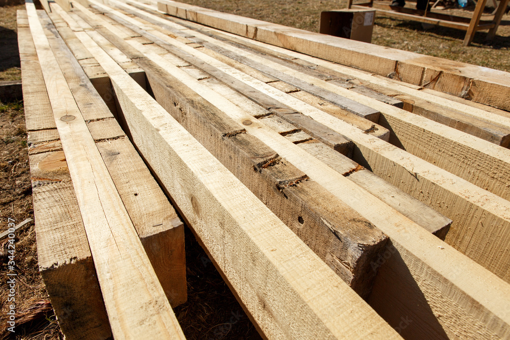 Timber and construction beams are lying on the construction site. Preparing for the construction of the roof Timber and construction beams are lying on the construction site. Preparing for the construction of the roof