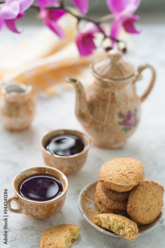 Homemade gluten-free cornmeal cookies on a light table, along with a coffee service and a yellow napkin in the background and an archidea branch