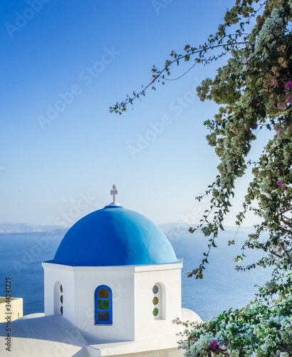 blue dome of Saint Nikolaos Peramataris orthodox church with flowers in Oia, Santorini island, Cyclades, Greece