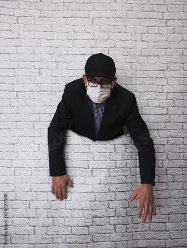 a man in a medical mask crawls out of a brick wall