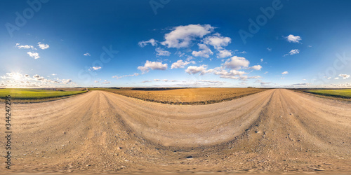Full spherical seamless panorama 360 degrees angle view on no traffic gravel road among fields in evening before sunset with clear sky in equirectangular projection, VR AR content