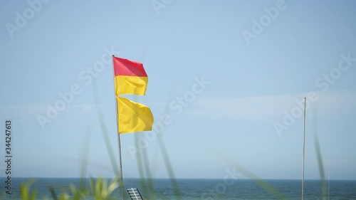 Lifeguard Baywatch Red Yellow Flag. Swimming allowed. Summer warm day blue Sky. Slow motion close isolated.

