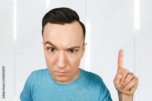 Fotografi Young frowns threaten man point finger, dressed in a blue t shirt