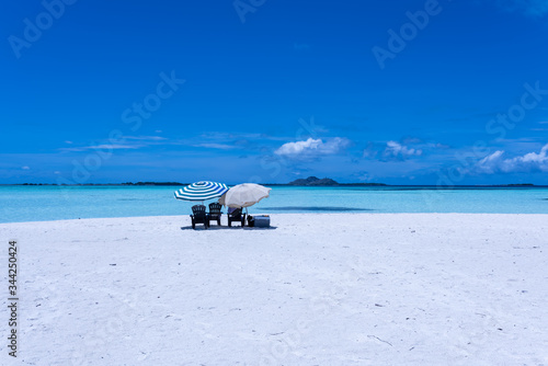 Los Roques Archipelago, Venezuela: view of isolated beach umbrellas in "Cayo Los Viejos" ("Saki Saki") in the caribbean sea with Gran Roque island in the background.
