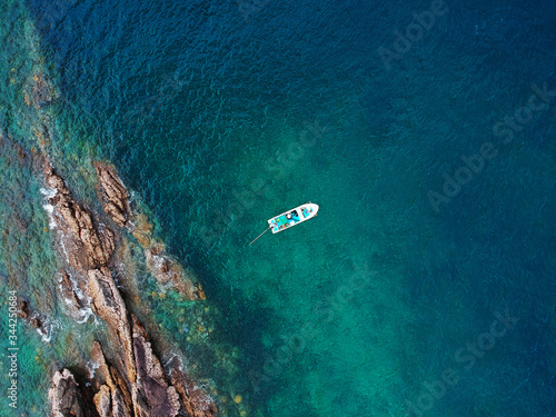 A small vessel floating in tropical clear sea over coral reef with beautiful seascape in summer. Aerial view on the sea taken from drone. © Phonphot