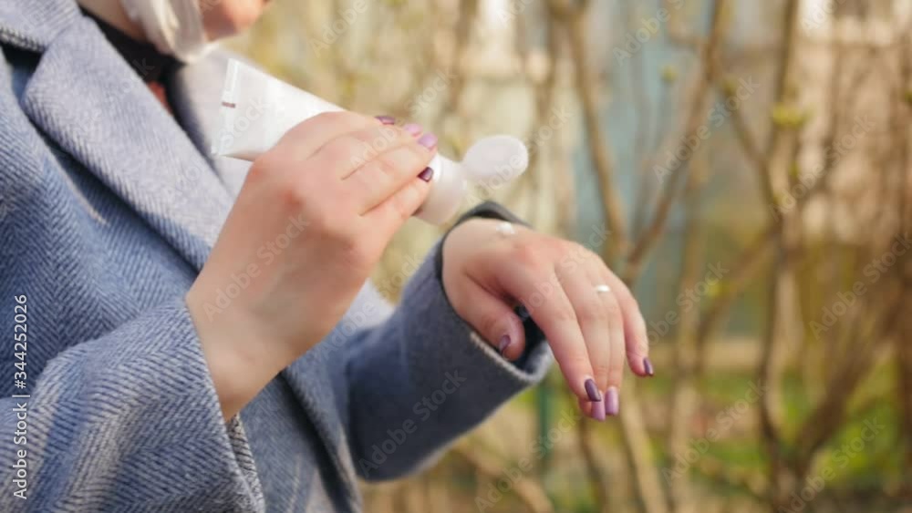 Woman's hands close-up. Girl smears cream on her hands on the street. Woman's hands close-up. Girl smears cream on her hands on the street.
