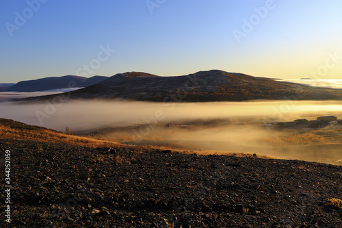 Norwegische Berglandschaft im Sonnenaufgang mit Nebelschwaden und blauem Himmel