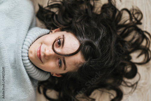 Close-up portrait of a charming European girl of 8 years old. She smiles lying on the floor. She has beautiful wavy, loose hair.