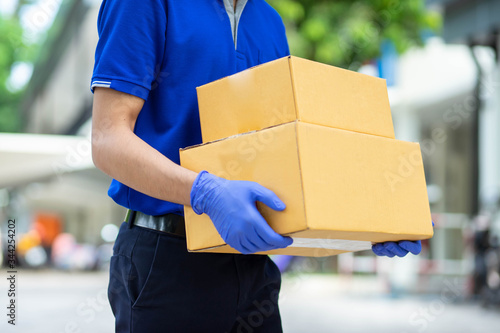 Delivery man put on gloves to hold cardboard boxes