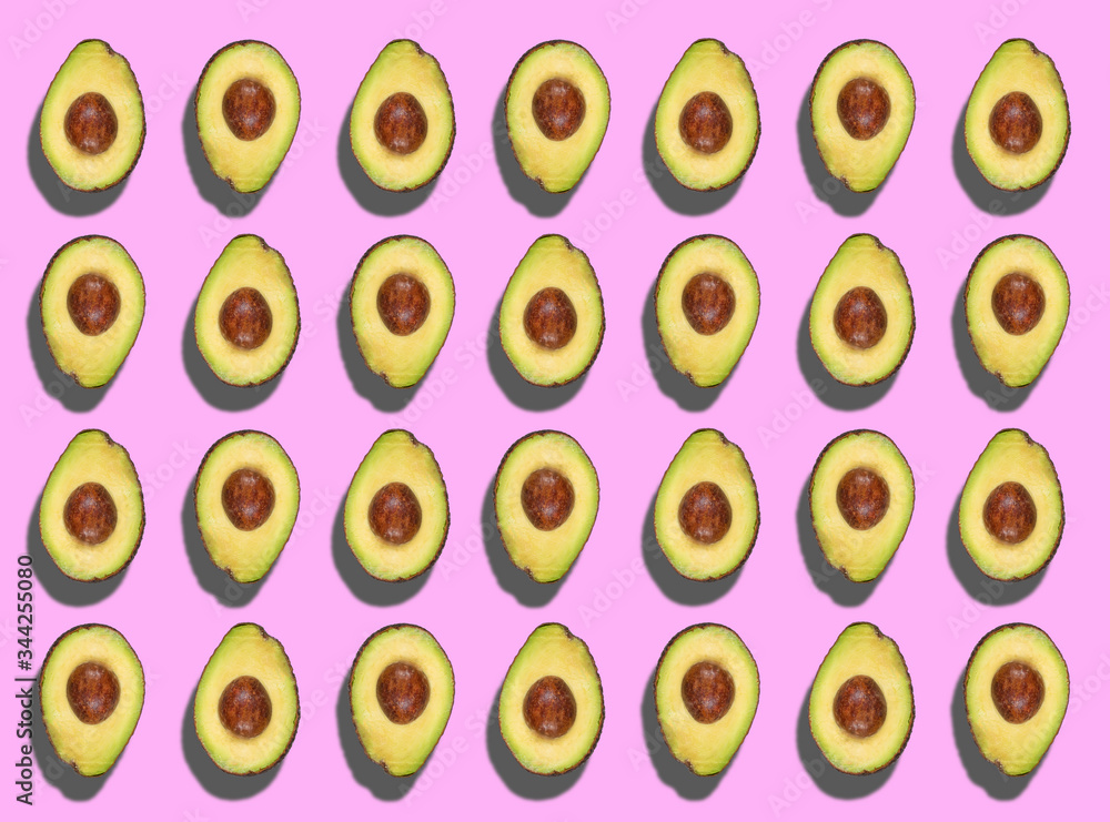 A colorful pattern of cut avocados spinning on a light violet background. Zenithal top view. A colorful pattern of cut avocados spinning on a light violet background. Zenithal top view.