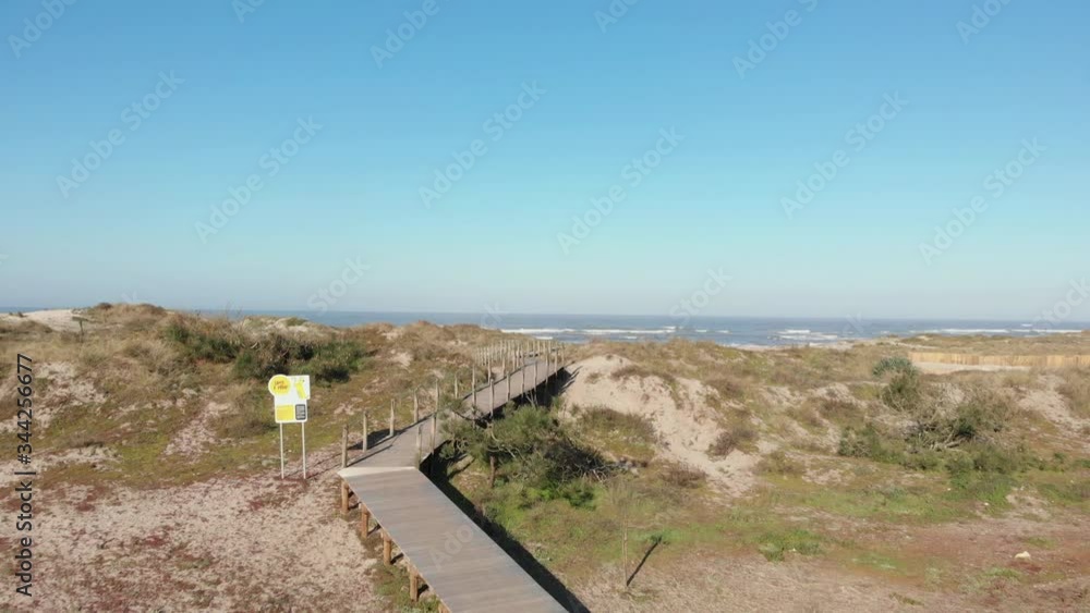 DRONE - view of dune fencing to control wind erosion and encourage dune stability. Stream flowing into the sea at the North Coast Natural Park, The Protected Landscape of Esposende Coast, Portugal. DRONE - view of dune fencing to control wind erosion and encourage dune stability. Stream flowing into the sea at the North Coast Natural Park, The Protected Landscape of Esposende Coast, Portugal.