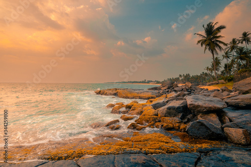 Rocks, stones and foamy waves at the ocean coast line under a beautiful sunset sky with clouds on Sri Lanka island. © stone36