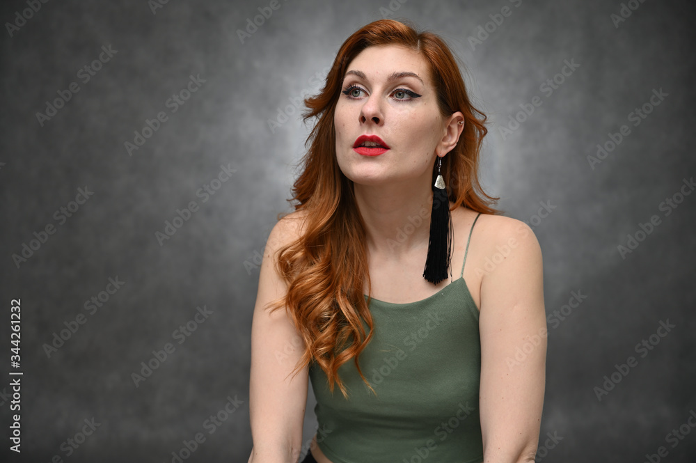 Portrait on a gray background of a pretty red-haired young woman. A model with great makeup posing in a green t-shirt in the studio. Portrait on a gray background of a pretty red-haired young woman. A model with great makeup posing in a green t-shirt in the studio.