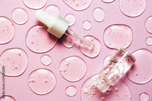 Liquid gel or serum drops with pipette on pink background in macro. Flat lay style. photo