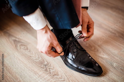 The Groom dressing up with classic, elegant shoes. Men's shoes are elegant shiny, man makes a knot, dressing the wedding.