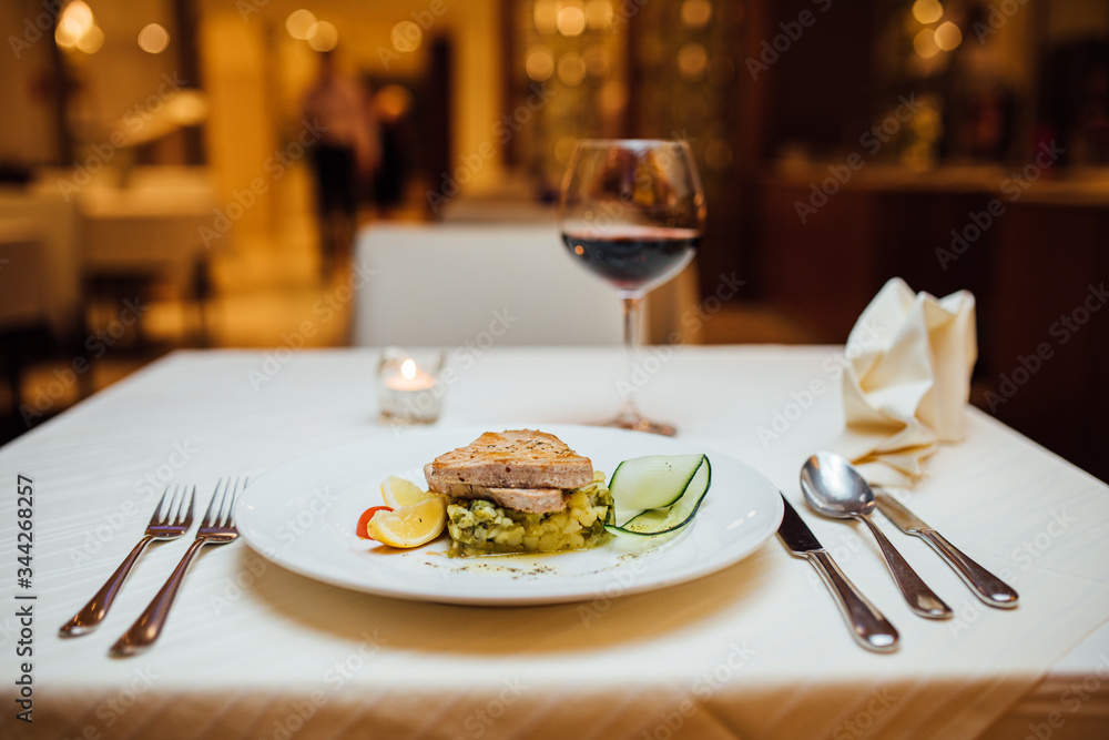 Tuna fish steak served over braised green vegetables with glass of wine.Small portion.Restaurant recipe recreation.Keto diet ingredients.Cooking at home.Healthy nutritious dinner for single person. Tuna fish steak served over braised green vegetables with glass of wine.Small portion.Restaurant recipe recreation.Keto diet ingredients.Cooking at home.Healthy nutritious dinner for single person.