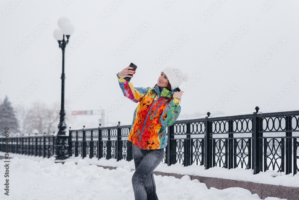 A young athletic girl takes a selfie on a frosty and snowy day. Fitness, recreation