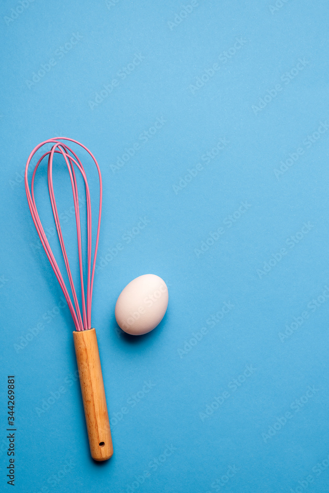 Kitchen whisk and a single egg, bake and cook concept Kitchen whisk and a single egg, bake and cook concept