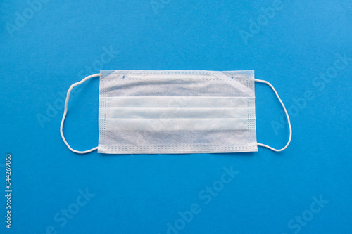 white medical respiratory mask on a blue background. Hospital or pollution protect face masking . Copy space 