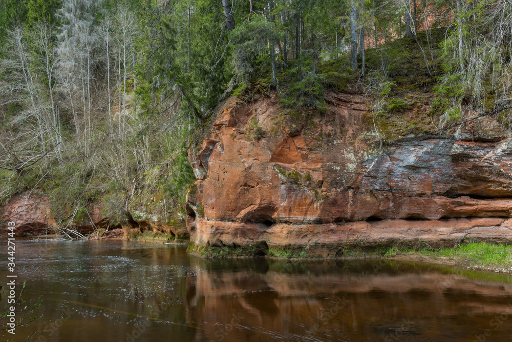 City Cesis, Latvia. River in spring with sandstone cliffs and caves.