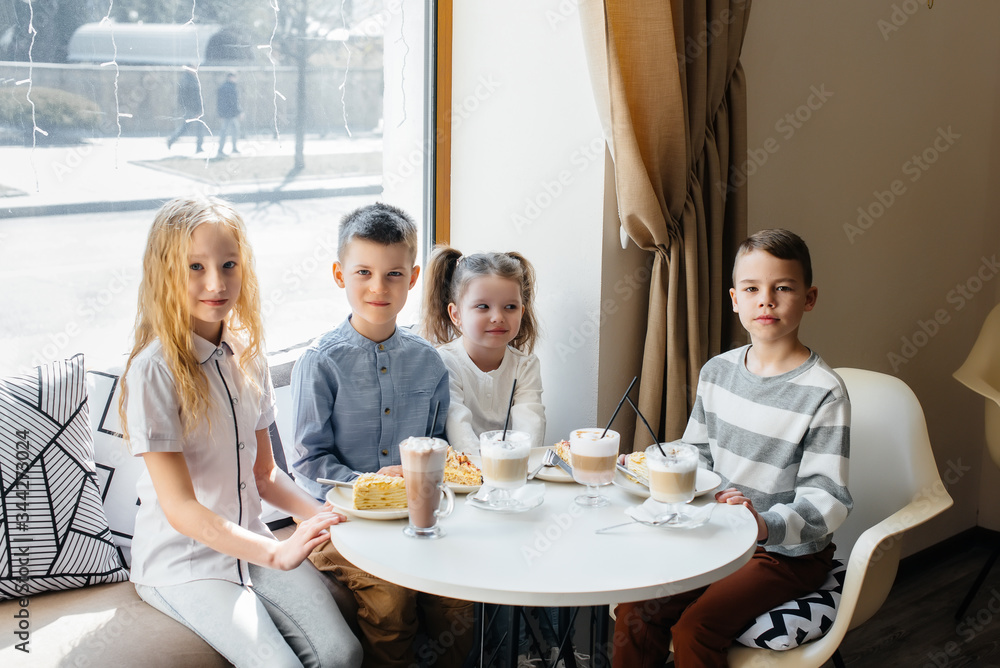 A large friendly company of children celebrate the holiday in a cafe with a delicious dessert. The day of the birth