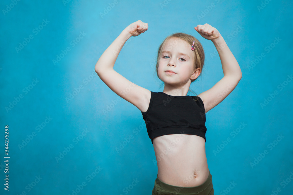 Happy pretten girl do sports and show muscles biceps on blue background. Happy pretten girl do sports and show muscles biceps on blue background.