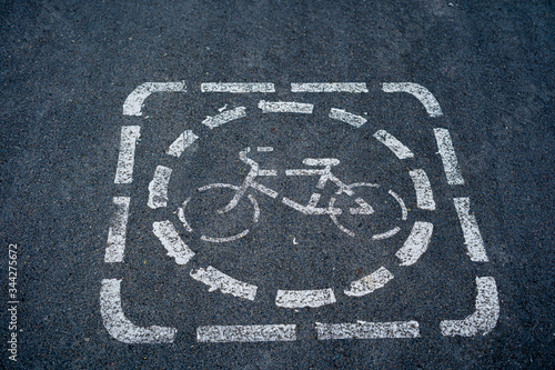 Top view of bicycle road sign painted with white color on dark grey asphalt road