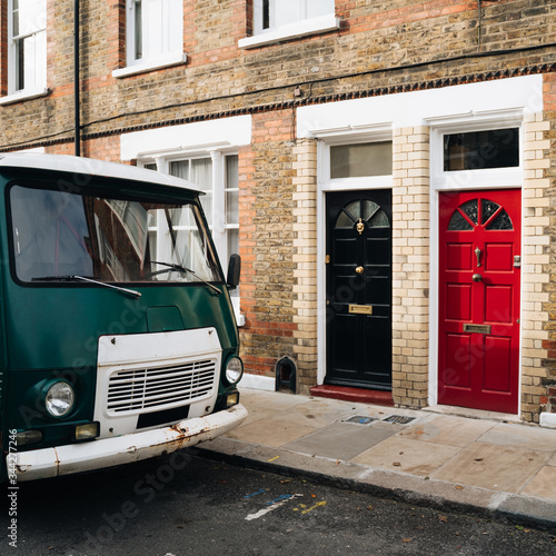 Colourful wooden doors and brick building and green old van in Columbia Road, London