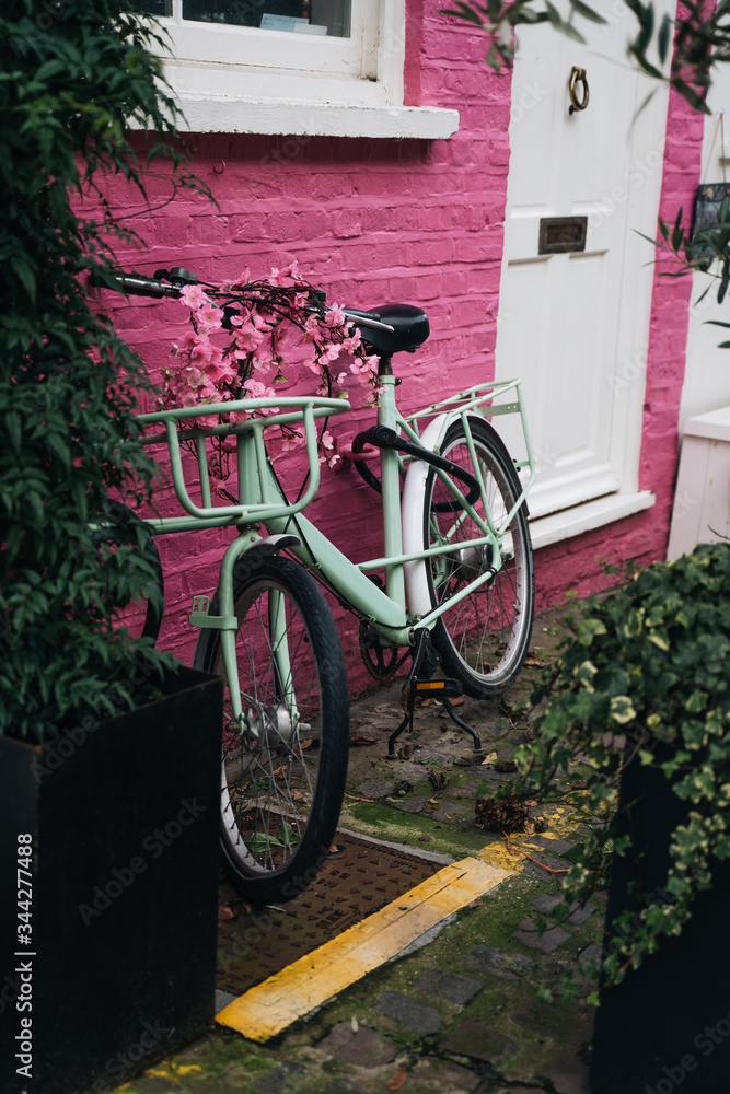 Classic bicycle parked on vibrant pink brick wall in London