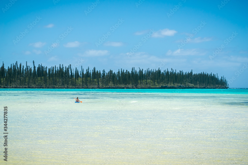 tropical beach with araucaria pines trees and couple in canoë kayak