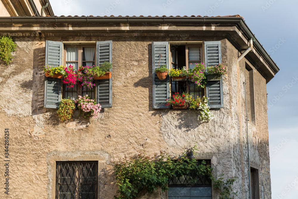 old stone building with wooden shutters and flower pots hanging from the windows