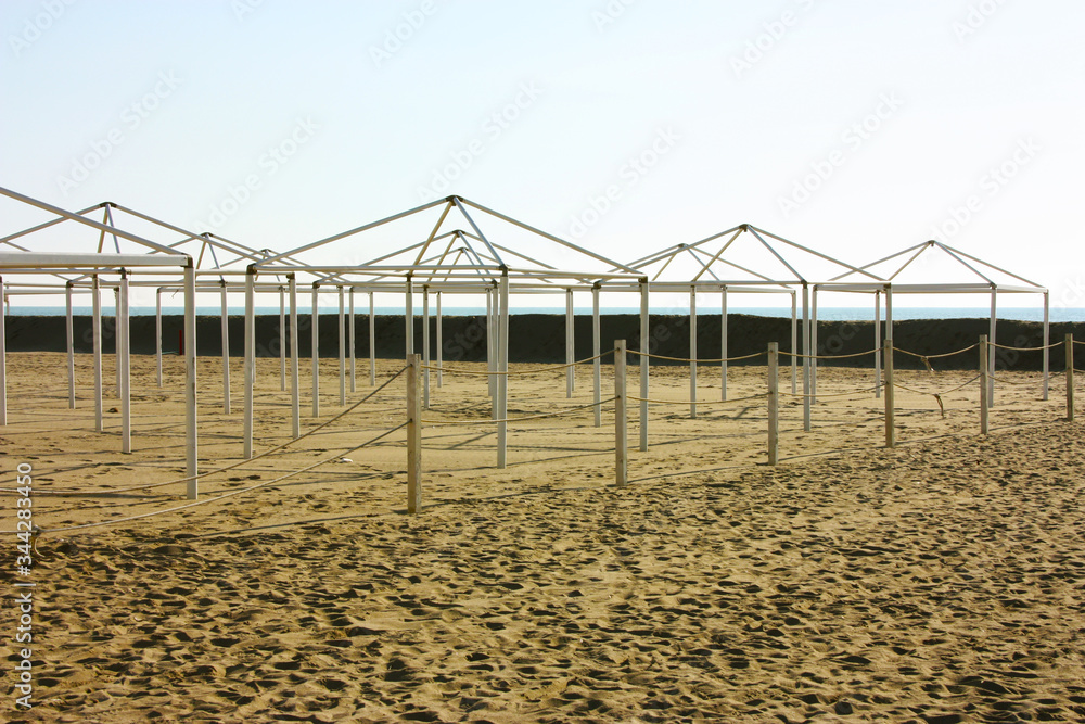 structures for desolate umbrellas and tents of unused bathing establishments alone without quarantine on the beach by the sea structures for desolate umbrellas and tents of unused bathing establishments alone without quarantine on the beach by the sea
