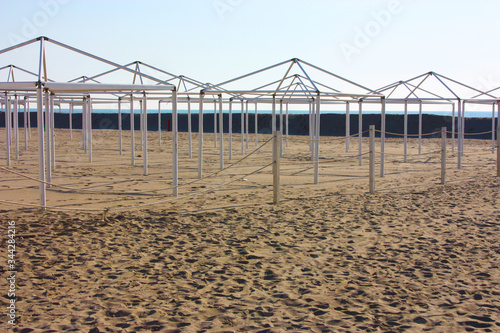 structures for desolate umbrellas and tents of unused bathing establishments alone without quarantine on the beach by the sea