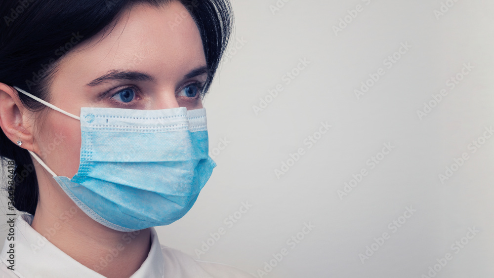 Portrait of a young European woman in a protective disposable medical mask. Concept of caronavirus Cavid 19 and human quarantine. Girl in a mask on a white wall. Masked medical worker. Portrait of a young European woman in a protective disposable medical mask. Concept of caronavirus Cavid 19 and human quarantine. Girl in a mask on a white wall. Masked medical worker.