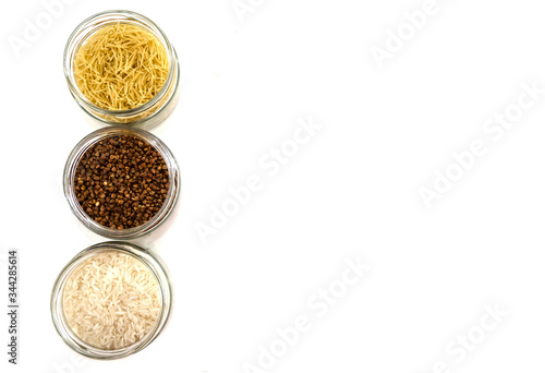 rice, buckwheat and pasta in glass jars on white. View from above. Copy space. Place for text.