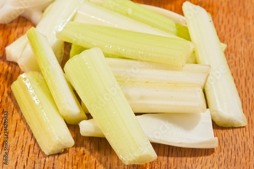 Top, front view, very close distance, of a pile of slices celery, on a wood cutting board