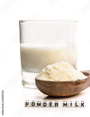 Full fat powdered milk in wooden spoon isolated on white