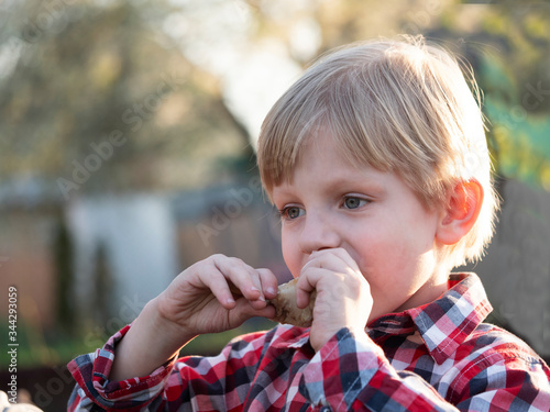 caucasian boy eats a chicken drumstick cooked on the BBQ delicious