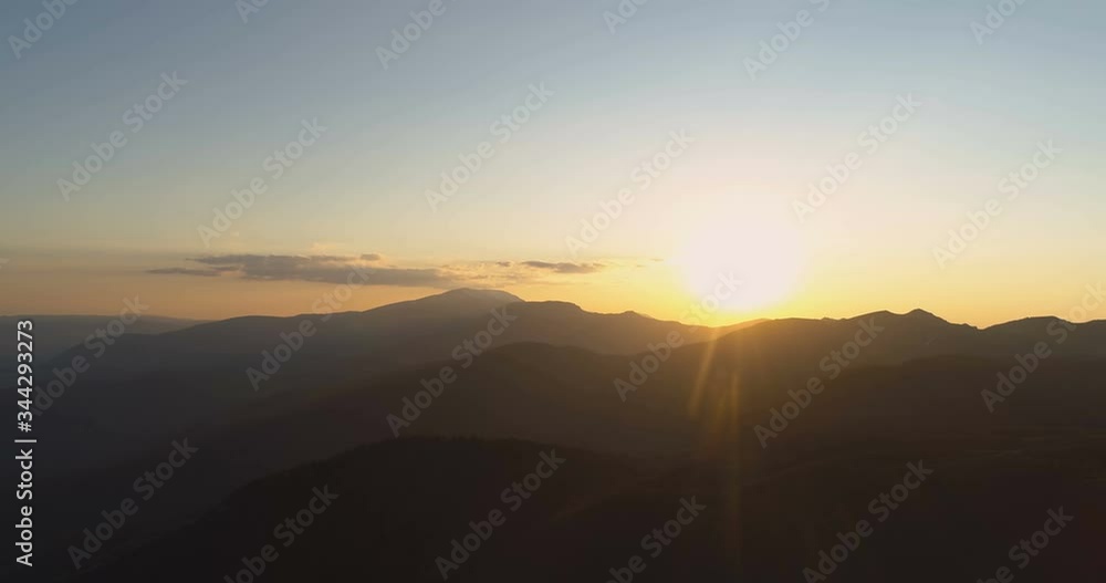 Golden sun shining over dark mountain peaks Golden sun shining over dark mountain peaks