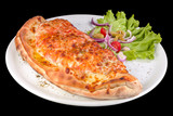 Calzone pizza with tomato sauce, bacon, ham, stewed mushrooms and yellow cheese on a plate, isolated on black background