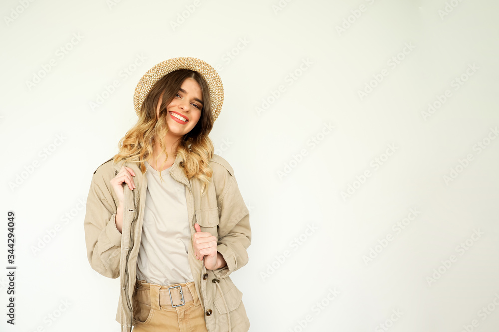 Young beautiful happy woman wearing neutral clothes and a hat on a white background. Young beautiful happy woman wearing neutral clothes and a hat on a white background.