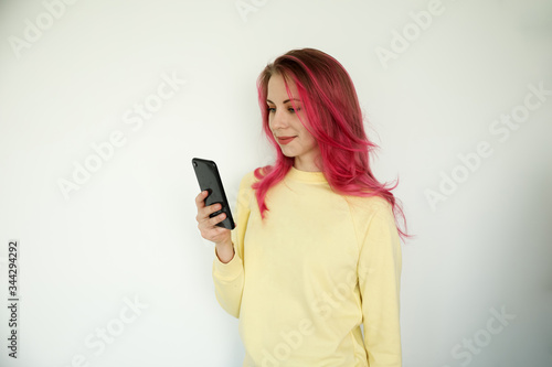 A young woman on her phone, wearing a yellow shirt on a white background.
