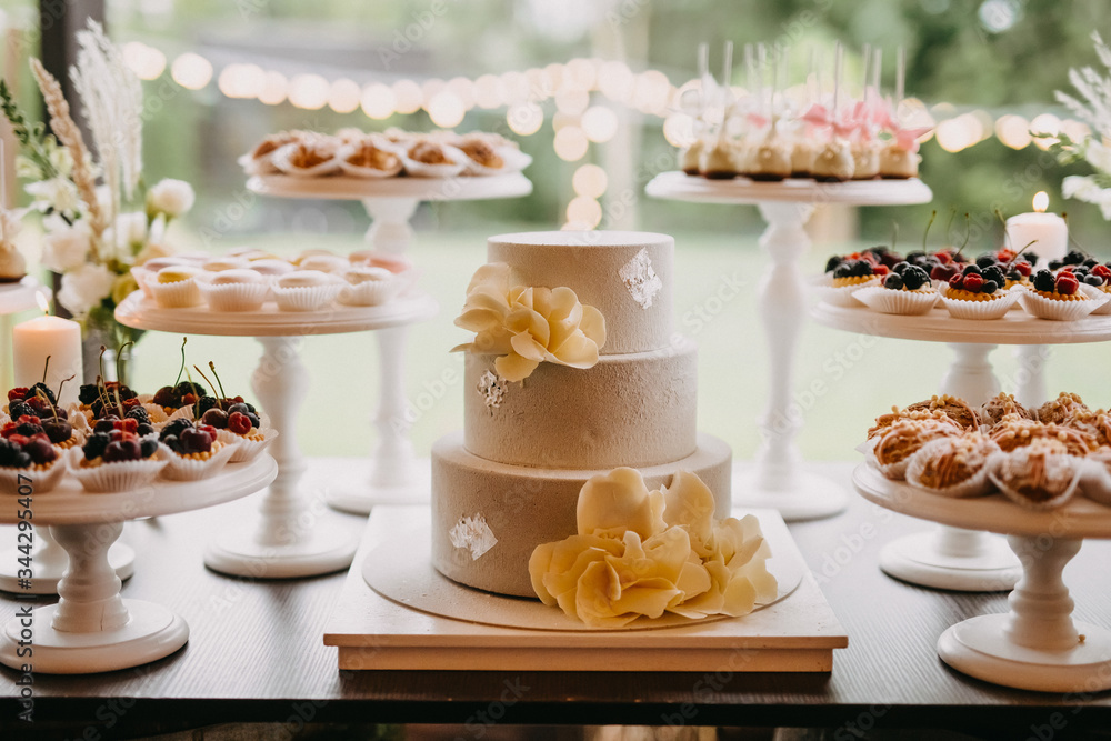Candy bar at a wedding with different sweets and a wedding cake, in pastel light colors.