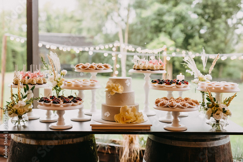 Candy bar at a wedding with different sweets and a wedding cake, in pastel light colors.