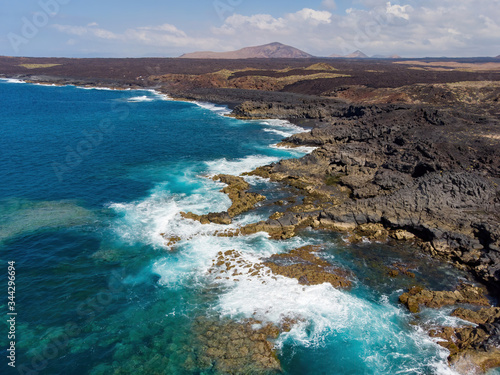 Aerial view of paradisiacal beach with black sand and volcanic scenery in Lanzarote, Canary Islands