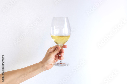 Woman hand holds gives a glass of champagne white wine on a white background. Place for text.