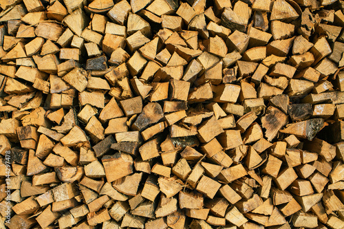 Prepared chopped wood. A stacked woodpile. Texture in the form of a wooden wall.
