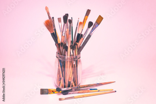 A lot of different dirty used paint brushes and creativity in the glass and on the table. -Image.