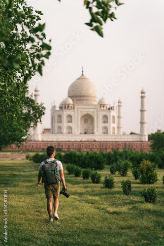 Beautiful shot of Taj Mahal at sunset with young man walking in garden